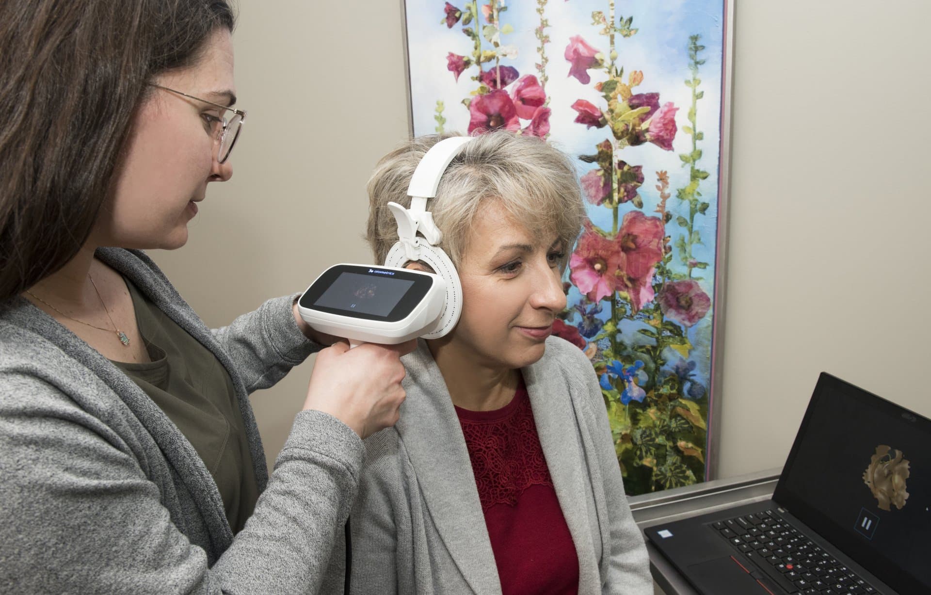 An audiologist fitting a hearing aid at the Audiology Clinic of Northern Alberta